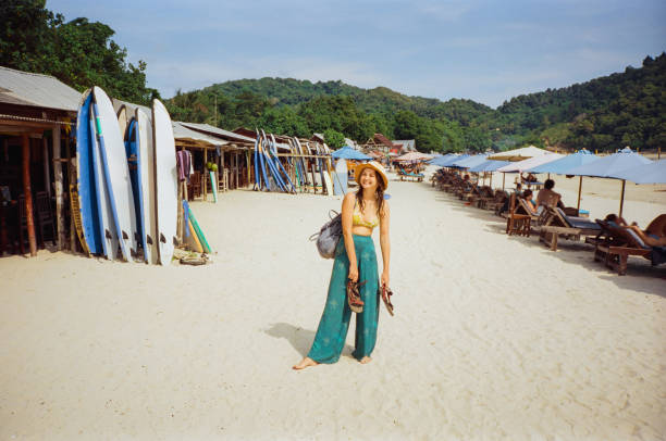 kobieta spacerująca po plaży z wypożyczalniami surfingowymi - ściana-kurtynowa-obrazy zdjęcia i obrazy z banku zdjęć