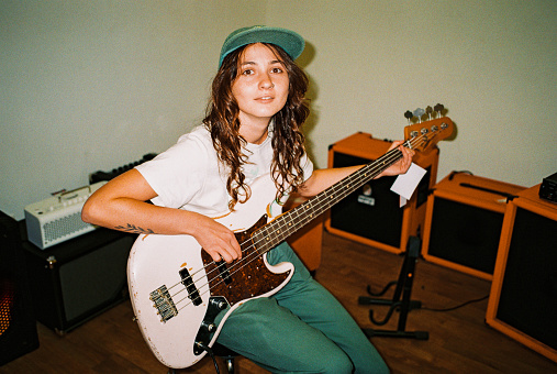 Portrait of woman  in cap playing bass guitar shot with flash on film camera
