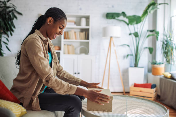 istock Happy woman opening a gift box at home 2150354823