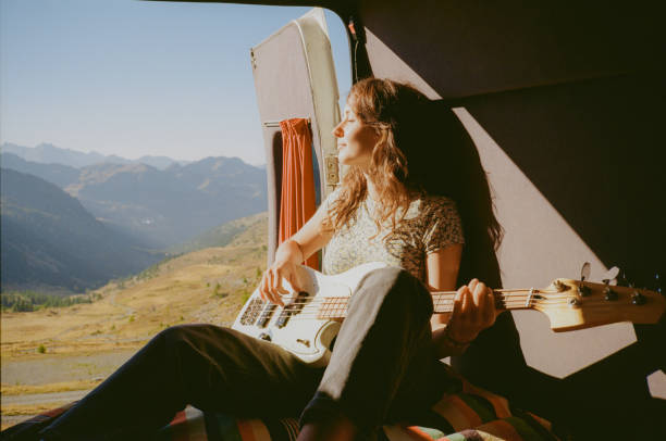 Woman with guitar in camper van in mountains