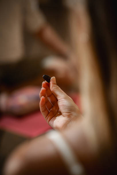 Unrecognizable woman's hand holds ceremonial cocoa bean in a ceremony.