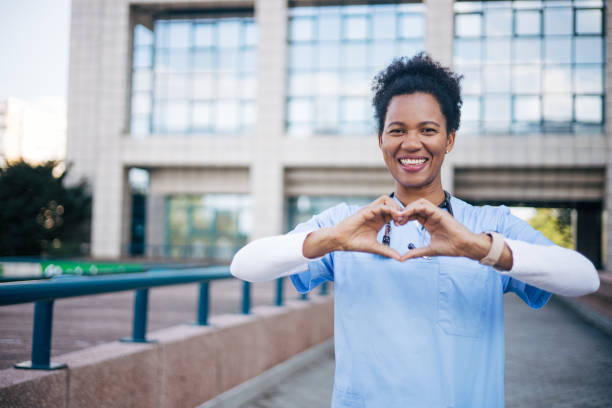 istock Smiling black doctor with curly hair makes a heart shape with her hand 2150358193