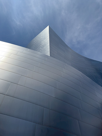Low-angle medium shot of a gleaming graceful glass section of the distinctive Walt Disney Concert Hall in Los Angeles