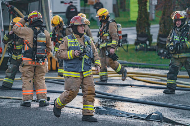 A firefighter stands on top of a firetruck, actively engaged in an emergency or operation in a Copenhagen suburb. The photo was taken on March 10, 2025, capturing a moment of bravery and firefighting in action.