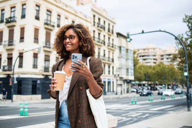 istock Happy woman using smartphone and drinking coffee on the move 2150360726