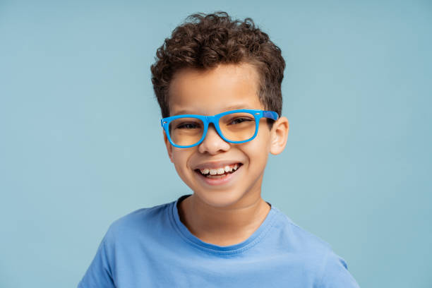 istock Little boy wearing stylish eyeglasses looking at camera, isolated on blue background 2150361501