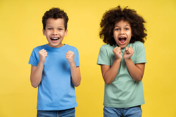 istock Two happy little African kids rejoicing winner success while standing in studio, looking at camera 2150361542