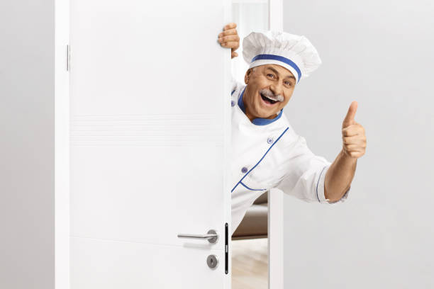 istock Mature chef in a uniform gesturing thumbs up behind a door 2150364788