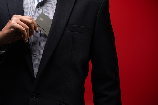 Close up hand of businessman holding credit card isolated red background.