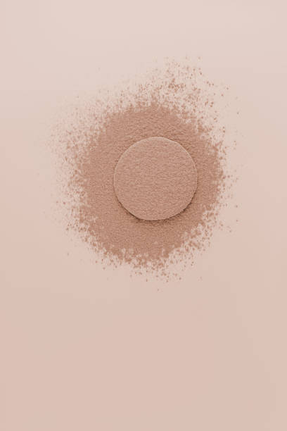 istock Bronze-toned loose powder is poured onto a round disc for applying makeup. background for design. A copy space. A sample of loose powder. 2150377717