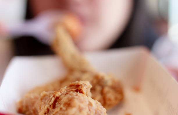 Woman eating fried chicken blurred background, Street food in thailand