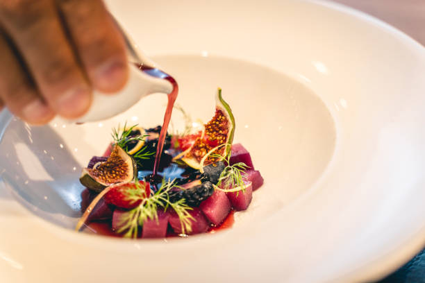 Hand pours sauce over fresh fruit at luxury restaurant, Ticinese restaurant