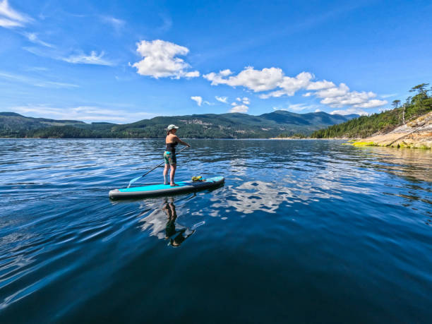 istock Woman paddles SUP board on calm bay 2150379042