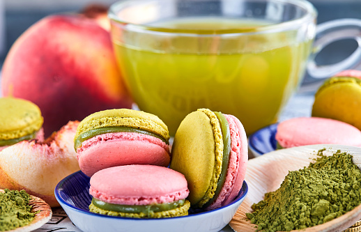 A delightful pairing of a bowl of colorful macarons next to a cup of antioxidant rich green tea, creating a perfect balance of indulgence and refreshment on the table