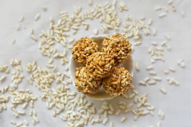 Close up view of bengali Traditional Puffed Rice Balls is a sweet made using puffed rice mixed with jaggery, other named Murmura Laddoo, Churmura Laddoo or Pori Urundai, flattened rice sweet ball or Chirar moa on white background. Selective focus. close up view of bengali traditional puffed rice balls is a sweet made using puffed rice mixed with jaggery, other named murmura laddoo, churmura laddoo or pori urundai, flattened rice sweet ball or chirar moa on white background. selective focus.