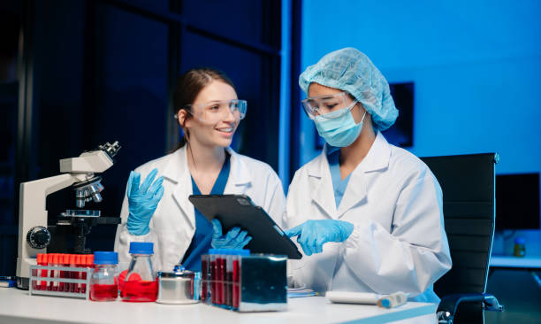 istock Modern Medical Research Laboratory Portrait of Two Scientists Working, Using Digital Tablet, Analyzing Samples, Talking. 2150379375