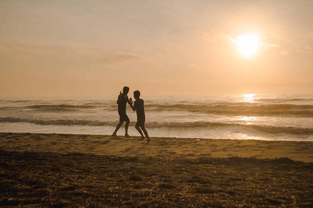 istock silhouette two man run on beach with sunrise and sea background 2150380302