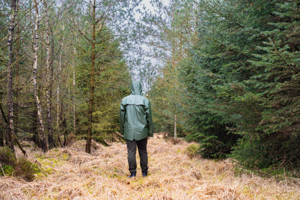 istock Man in green raincoat walking in the forest 2150380777