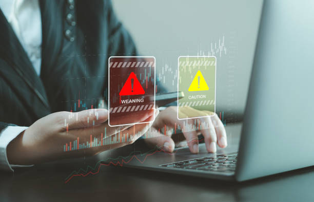 istock Businessman using smartphone and notebook at work desk with warning sign for caution in investment, warning of economic situation, risk in business investment. 2150382727