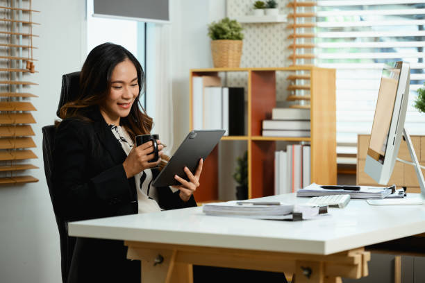 istock Charming businessman drinking coffee at working desk and reading email on digital tablet 2150383435