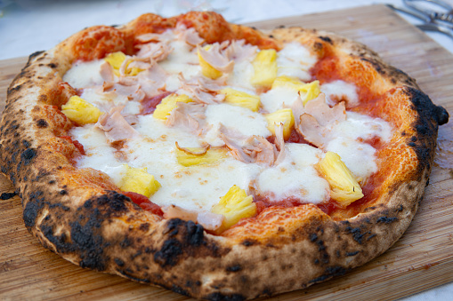 belongs to a series 14. A pizza with pineapple and chicken toppings sits on a wooden cutting board.