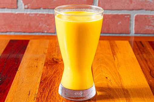 Glass of fresh carrot juice on the blue wooden background and copy space
