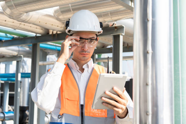 istock Portrait Asia male engineer in protective workwear is performing a conducts system check with use tablet computer at rooftop building 2150384535