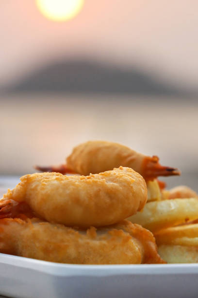 Stock photo showing close-up view of an appertiser (starter) of prawn tempura with French fries. Tempura is deep-fried pieces of seafood coated in batter.