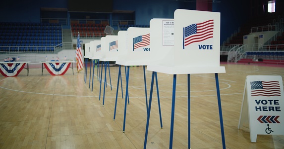 Voting booths with American flag logo at polling station. National Election Day in the United States of America. Presidential race and elections coverage. Civic duty, patriotism and democracy concept.