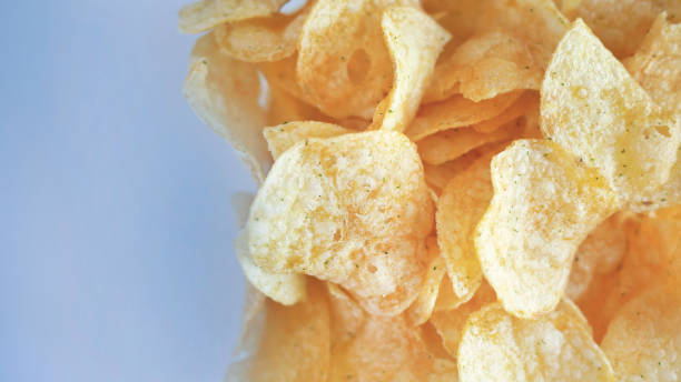 istock Close up crisp yellow potato chips over a plain background, still life, deep fried, healthy, snack, vegan food, tasty Golden appetizing 2150387204