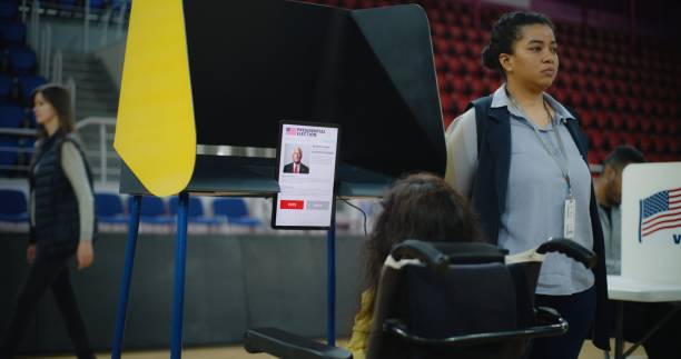 istock Woman with SMA in wheelchair votes in voting booth on tablet computer 2150387335