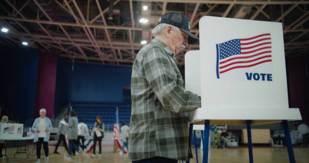 istock Elderly voter with bulletin in hands comes to voting booth 2150388039