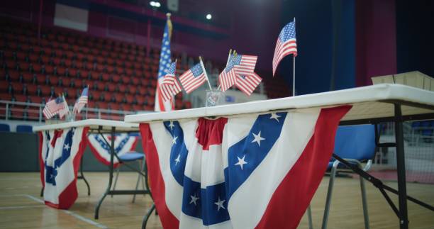 istock Table for voting registration with American flags stands at polling station 2150389805