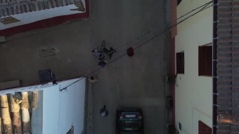 overhead aerial drone shot of elderly people walking through a rustic town between houses