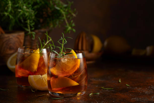 istock Cocktail with ice, rosemary and lemon slices on the old brown table. 2150390044