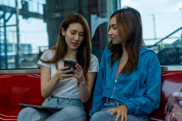 istock Two Young Women with Smartphone and Tablet on Train. 2150392374