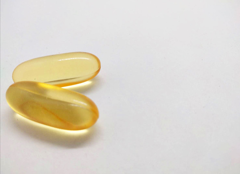 The imagery presents an array of fish oil capsules, poised elegantly against a pristine white backdrop, distinctly isolated for emphasis. Each capsule encapsulates the essence of pure fish oil, radiating a sense of health and vitality. Their elongated shapes and smooth surfaces exude a refined simplicity, suggesting the promise of wellness within. The translucent quality of the capsules offers a glimpse into the golden liquid contained within, hinting at its richness and purity. Soft, diffused lighting enhances the capsules' appearance, casting gentle shadows that accentuate their contours and add depth to the composition. Whether for nutritional supplements, skincare, or culinary endeavors, these fish oil capsules symbolize the essence of vitality and well-being, promising a dose of nourishment and vitality with every serving.