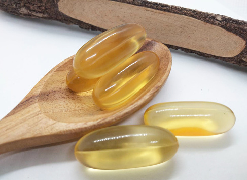 The imagery presents an array of fish oil capsules, poised elegantly against a pristine white backdrop, distinctly isolated for emphasis. Each capsule encapsulates the essence of pure fish oil, radiating a sense of health and vitality. Their elongated shapes and smooth surfaces exude a refined simplicity, suggesting the promise of wellness within. The translucent quality of the capsules offers a glimpse into the golden liquid contained within, hinting at its richness and purity. Soft, diffused lighting enhances the capsules' appearance, casting gentle shadows that accentuate their contours and add depth to the composition. Whether for nutritional supplements, skincare, or culinary endeavors, these fish oil capsules symbolize the essence of vitality and well-being, promising a dose of nourishment and vitality with every serving.