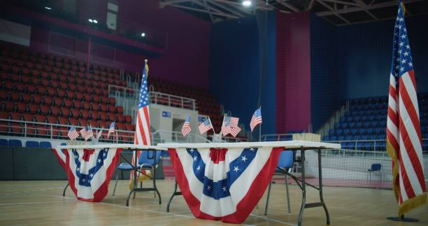 istock Table for voting registration with American flags stands at polling station 2150393994