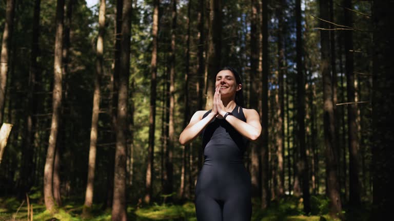A young woman does yoga and meditates in the forest.