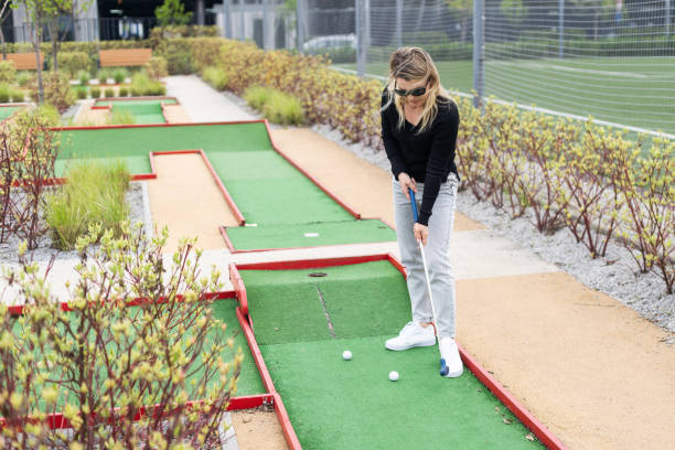 istock Woman playing mini golf and trying putting ball into hole. Summer leisure activity 2150395829