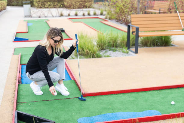 istock Woman playing mini golf and trying putting ball into hole. Summer leisure activity 2150396083