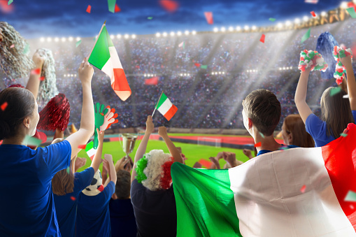 Italy football supporter on stadium. Italian fans on soccer pitch watching team play. Group of supporters with flag and national jersey cheering for Italia. Championship game. Forza Azzurri