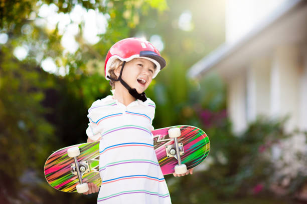 Kid with skateboard. Child riding skate board. Healthy sport and outdoor activity for school kids in summer. Sports fun. Helmet for safe exercise. Boy skater in sunny park. Children training.