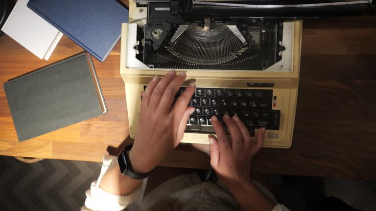 A woman typing on a typewriter, slow motion top-down angle from above.