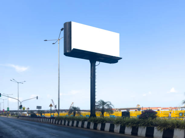 istock Billboard mockup outdoors. An empty roadside outdoor against blue sky background for presentation, blank commercial mock-up, ooh, poster, banner, hoarding, dummy placement for ads, branding 2150400252
