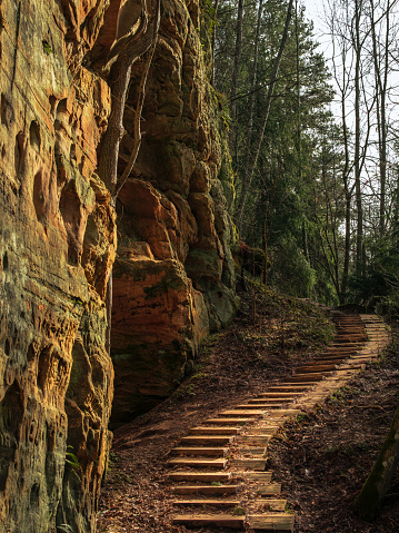 Curved steps gracefully ascend the rugged terrain next to Licu-Langu cliffs in Latvia, offering a poetic journey amidst nature's grandeur.