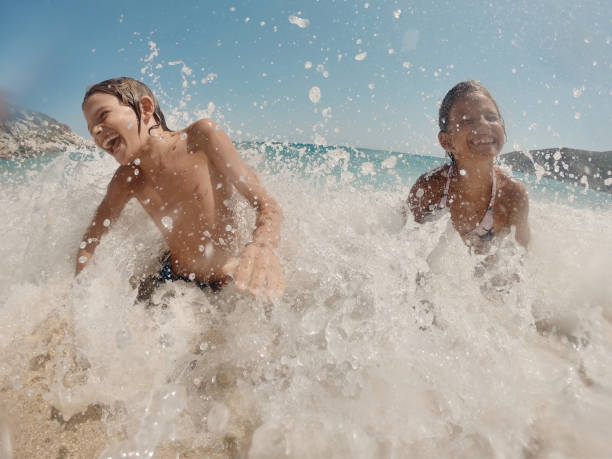 istock Young caucasian children jumping into waves 2150401089