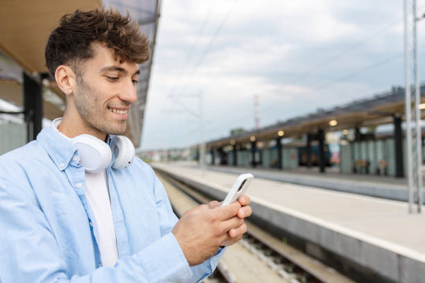 istock Young man at the train station using smart phone 2150401861
