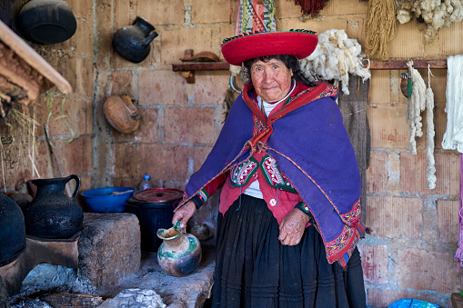 Portrait of Older Quechua indigenous lady weaver in the famous town of Chinchero heating water to create colored pigments and looking at the camera